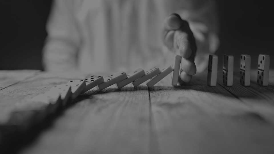 IGI Due Diligence hand holding dominoes from tumbling  black and white