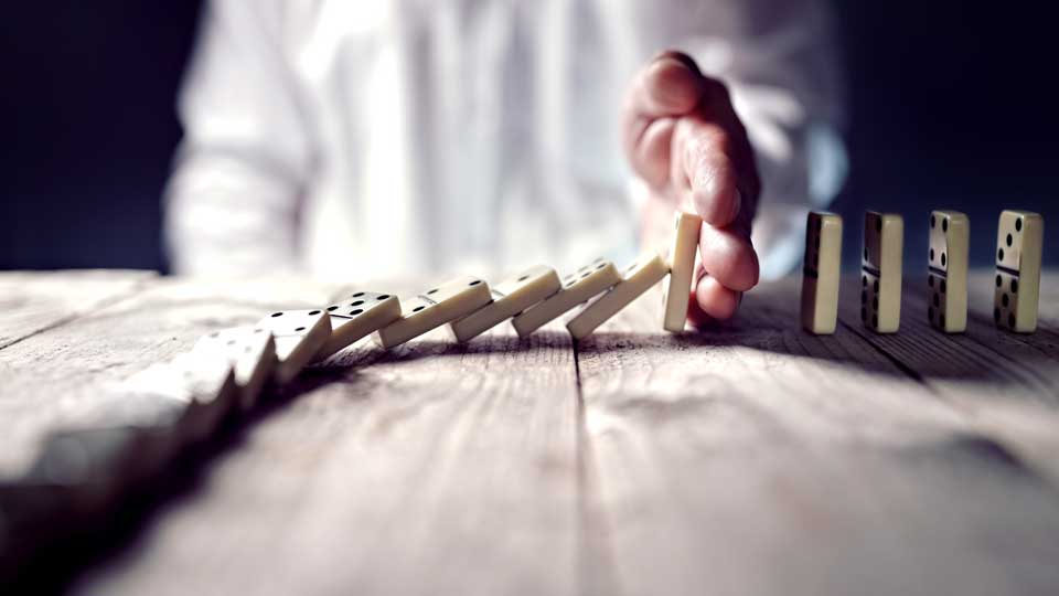 IGI Due Diligence hand holding dominoes from tumbling 